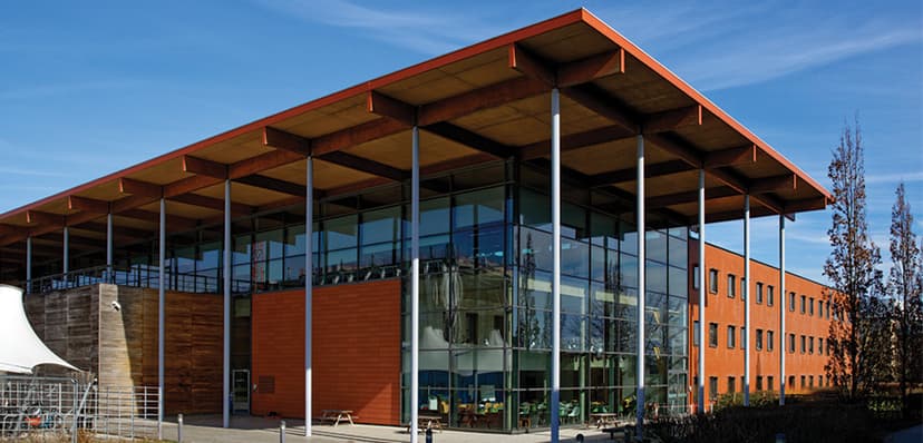 Modern glass-fronted William Gates Building at Cambridge University Computer Laboratory with distinctive orange trim and overhanging roof